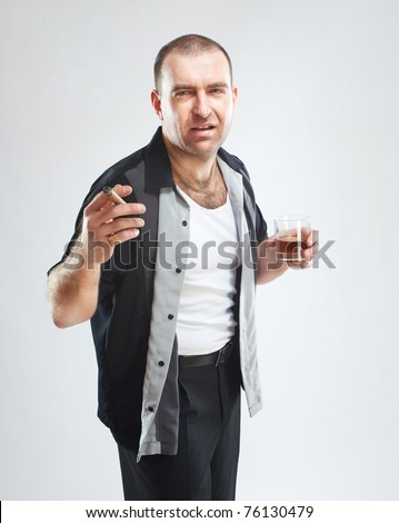 Portrait of serious tough guy with cigar and glass of alcohol, studio shot