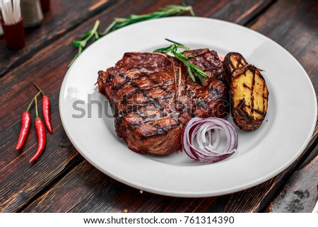 A large steak with spices and vegetables on the grill