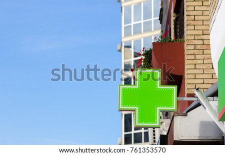 Green cross pharmacy sign or symbol on the building facade view from the street