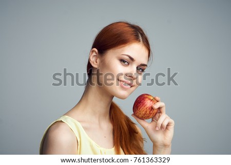 Young beautiful woman on a gray background holds an apple.