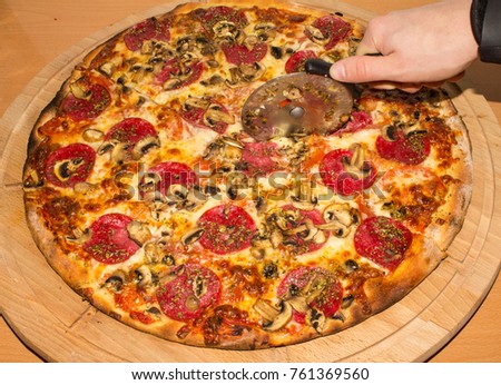 A large pizza that is cut with a knife.