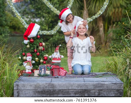 outdoor portrait of two child girls with chritmas tree in green park, christmas in summer, xmas in park