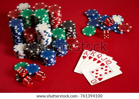 Casino gambling poker equipment and entertainment concept - close up of playing cards and chips at red background. Royal flush heart.