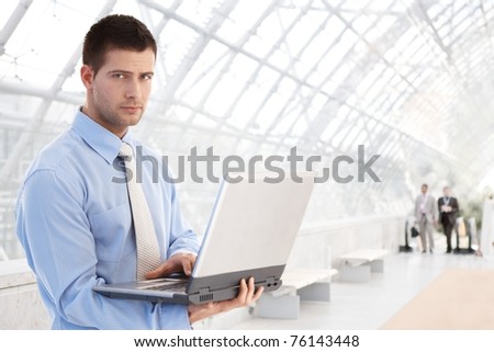 Handsome young businessman working on laptop at modern office lobby.?