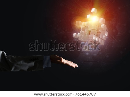 Close of businessman hand holding cube figure as symbol of innovation, mixed media