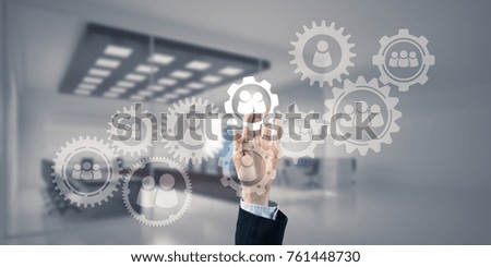 Close of businesswoman hand touching gears on screen with finger and office at background