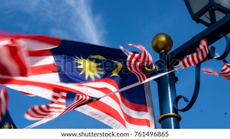 Waving Malaysian flags over the pole in a sunny day blue sky (selective focus)