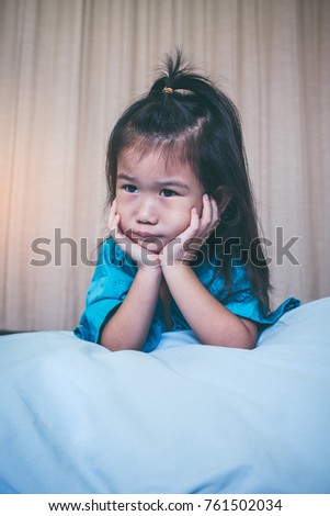 Illness asian child on sickbed and looking away, admitted in hospital. Unhappy girl feeling sad, bored, kid emotion. Concept for depression stress or frustration. Vintage film filter effect.