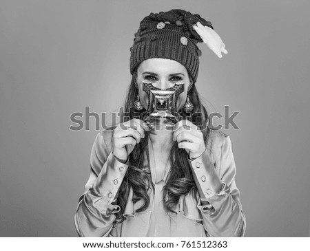 Stunning season. modern woman in funny Christmas hat isolated on grey background holding Eiffel Tower in front of face