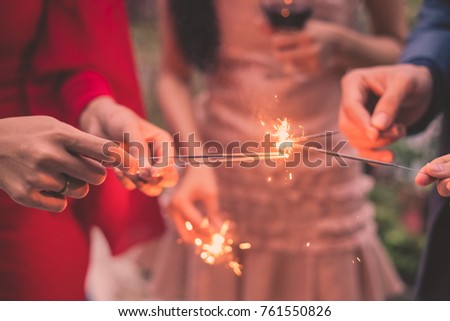 Young people holding fireworks at a party.
