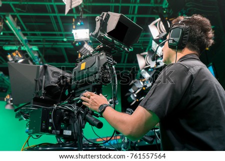 Cameraman taking a broadcast camera in broadcast television virtual green screen studio room. Royalty-Free Stock Photo #761557564