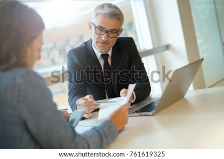 Woman in banker's office signing financial loan for project Royalty-Free Stock Photo #761619325