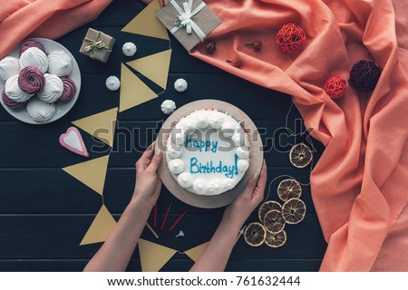 Cropped image of woman putting birthday cake on a table