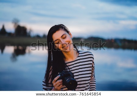 girl photographer in a striped blouse with a camera looking into the lens and smiling, portrait
