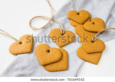 Spilled ginger heart cookies at grey cotton cloth at white background