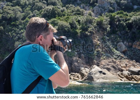 A tourist is photographing the Corsican coast in the Golfe de Porto. This is a famous place for many tourists on the Mediterranean coast.
