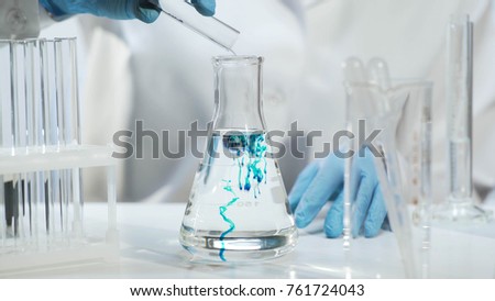 Chemist pouring substance into conical flask with liquid, chemical experiment Royalty-Free Stock Photo #761724043