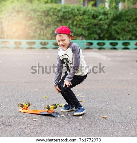 Little urban boy with a penny skateboard. Young kid riding in the park on a skateboard. City style. Urban kids. Child learns to ride a penny board