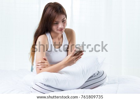 Happy woman  using phone while sitting on bed at his modern home people working mobile devices.Blurred background