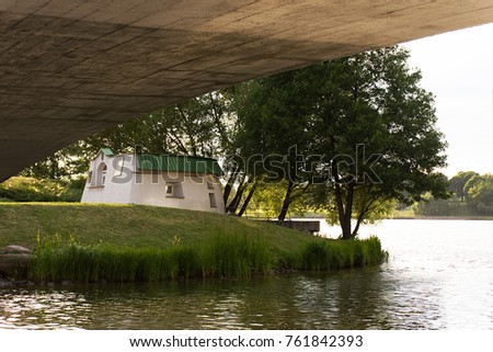 Embankment of the Svisloch River, Minsk. View of a white house on the embankment under a warm summer rain. 