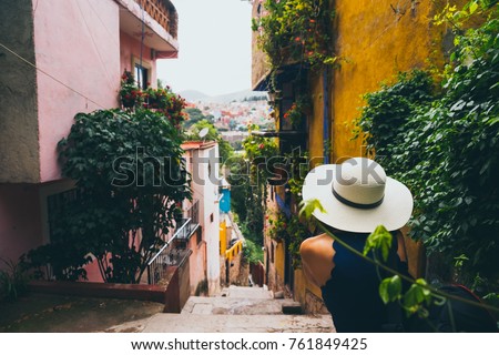 Woman with a hat sitting in a Guanajuato alley enjoying the view of the town Royalty-Free Stock Photo #761849425