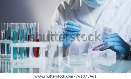 Cosmetology lab assistant preparing organic substance for anti-aging cream Royalty-Free Stock Photo #761873461