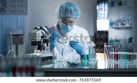 Lab worker dripping sample onto laboratory glass to research cloning process Royalty-Free Stock Photo #761873569