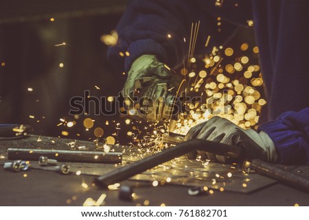 Creative and colored, horizontal image of man working with steel pipe, producing golden sparks on the work surface.