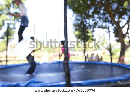 Blurred background. Young people and kids jumping on a trampoline.