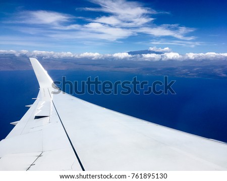 View of airplane wing with winglet, Pacific Ocean, and Mauna Kea mountain in the distance, before landing at Kona Big Island, Hawaii Royalty-Free Stock Photo #761895130