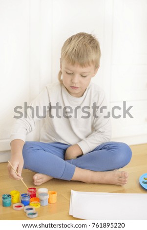 boy painting a picture with multicolored tools