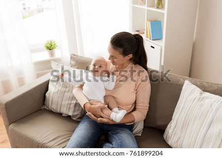 family, motherhood and people concept - happy mother with little baby boy sitting on sofa at home