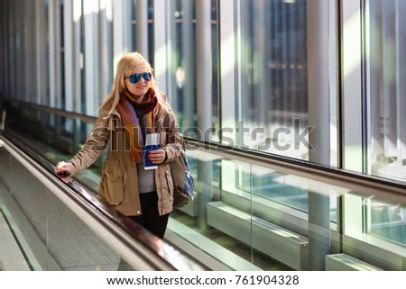 Young woman traveler in international airport with backpack holding passport in her hand