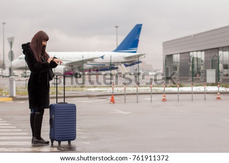 Beautiful girl with travel suitcase at the airport. Airplane in the background