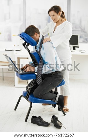 Masseur giving neck massage to businessman in office.?