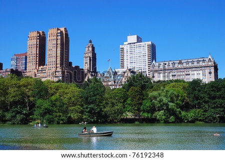 New York City Central Park with Manhattan skyline skyscrapers and blue sky with boat in lake.