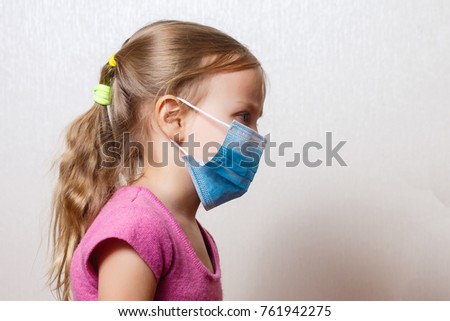 A little girl is in a non-permanent medical mask.