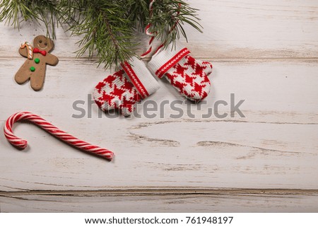Christmas candy, ginger man, pine branch and knitted read and white mitten toys at wooden background