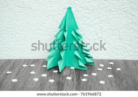 Cartoon paper evergreen tree and small snow flakes on dark wooden board. Hand made Christmas tree. Ecological zero waste winter decor. 