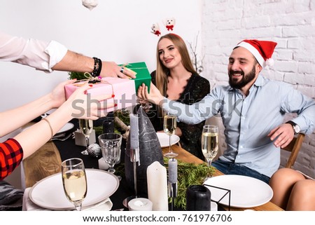 Picture showing group of friends celebrating Christmas at home and giving presents to each other