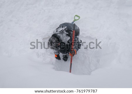 Young boy is playing in a fresh powdery snow, using shovels to dig a tunnel. Big Bear Valley, California. Winter fun activities. 