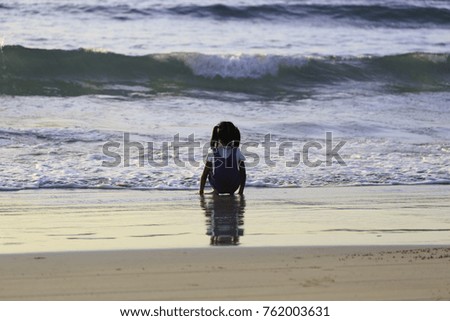 girl sitting on the beach in a light summer dress, watching the wave