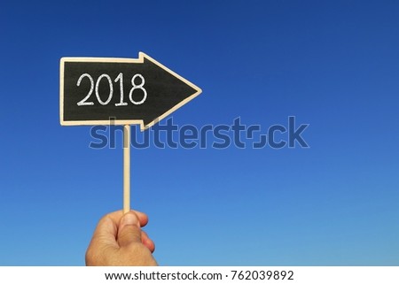 2018 word on the chalkboard arrow shape against the blue sky