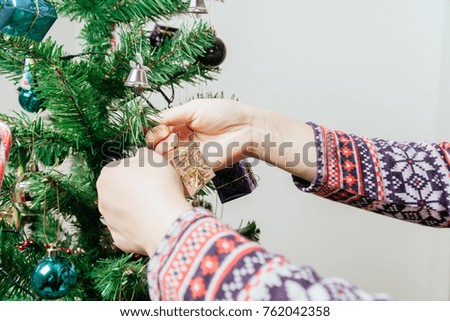 Christmas preparation: female hands decorating Christmas tree.