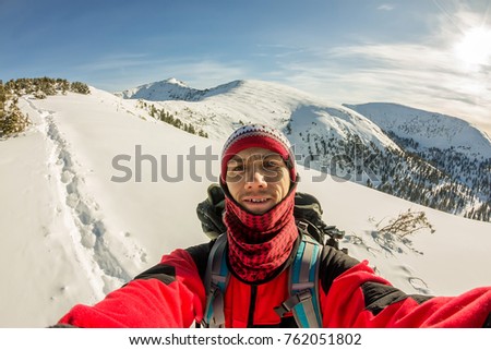 Selfi male traveler with a backpack in the winter mountains.