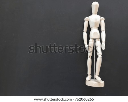 Wood doll standing on black color background with space writing space