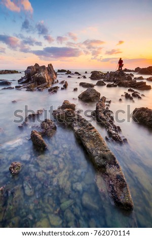 Amazing mossy rocks formations with silhouette person at Pandak Beach, Terengganu in long exposure technique. (blurry grain soft focus noise visible)