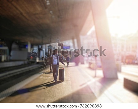 Asain man is hauling luggage at the public train station in Europe with light and blur background