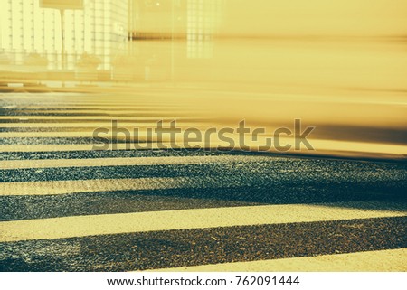 Urban city, light from the shop windows reflected on the road on which fast moving cars. View from the level of asphalt