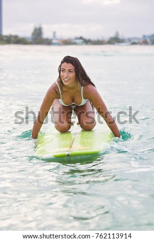 Beautiful Young Woman at the beach on her surfboard